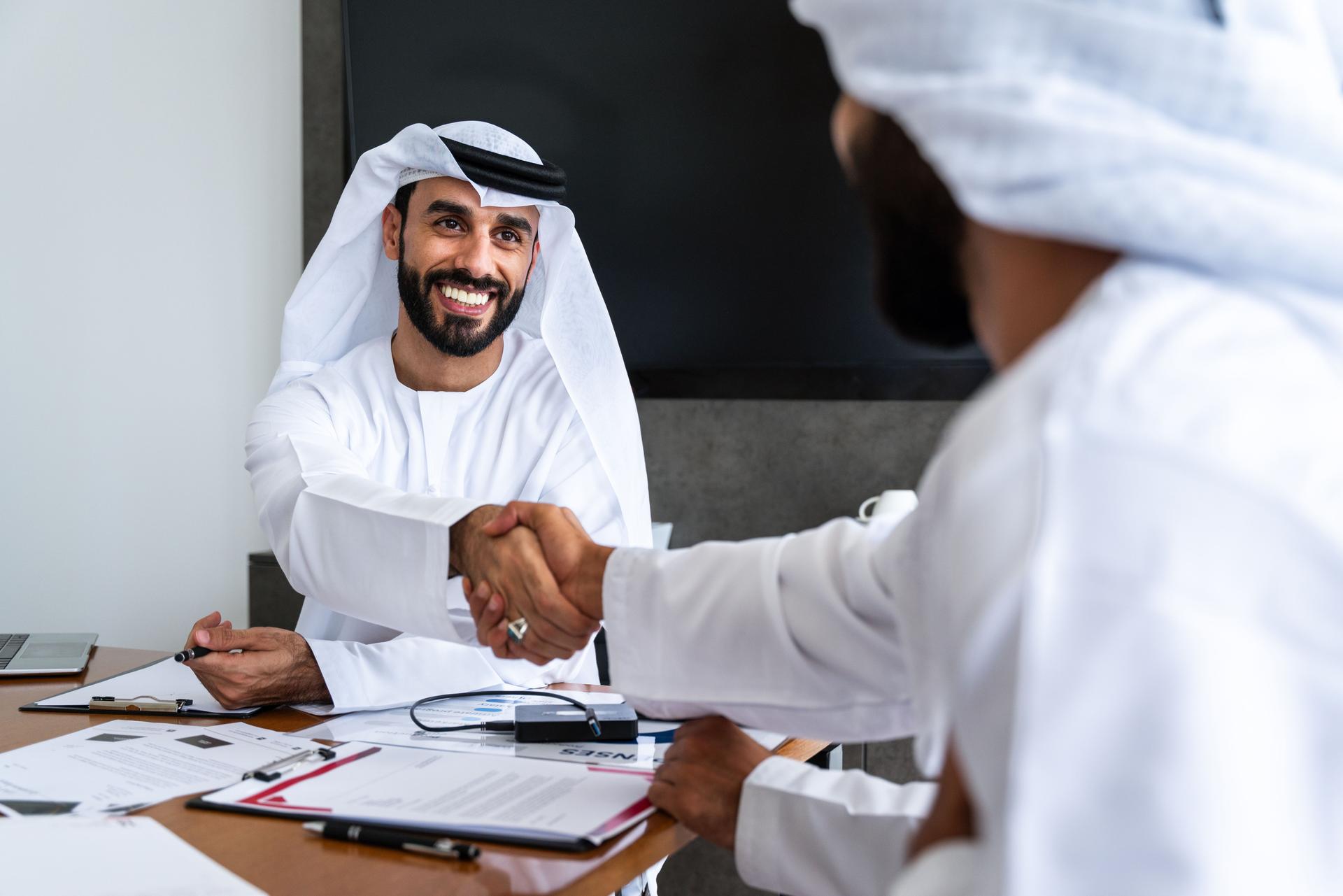 Arab businessmen wearing emirati kandura meeting in office for business deal